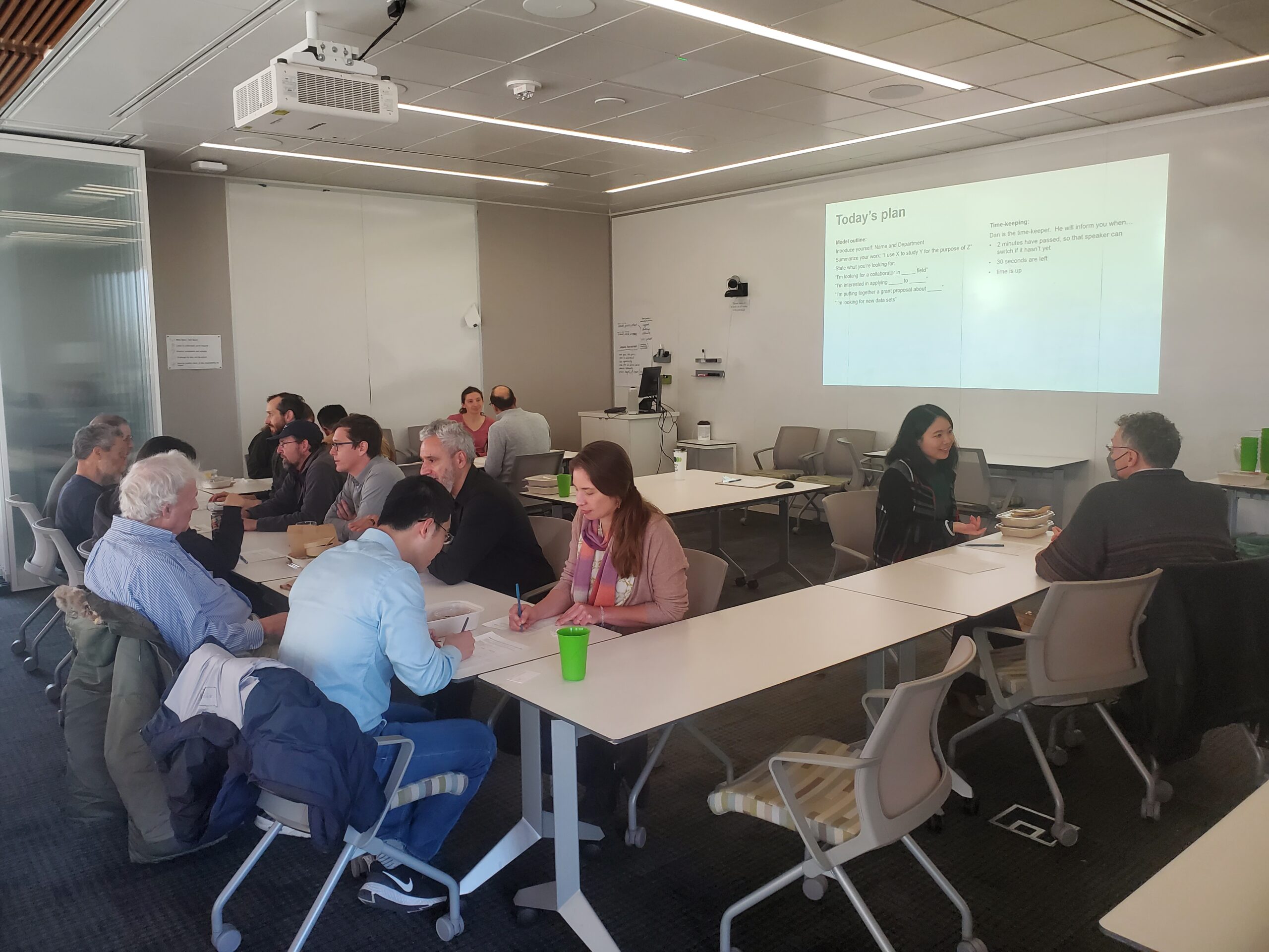 people sitting at tables speaking to one another with some writing