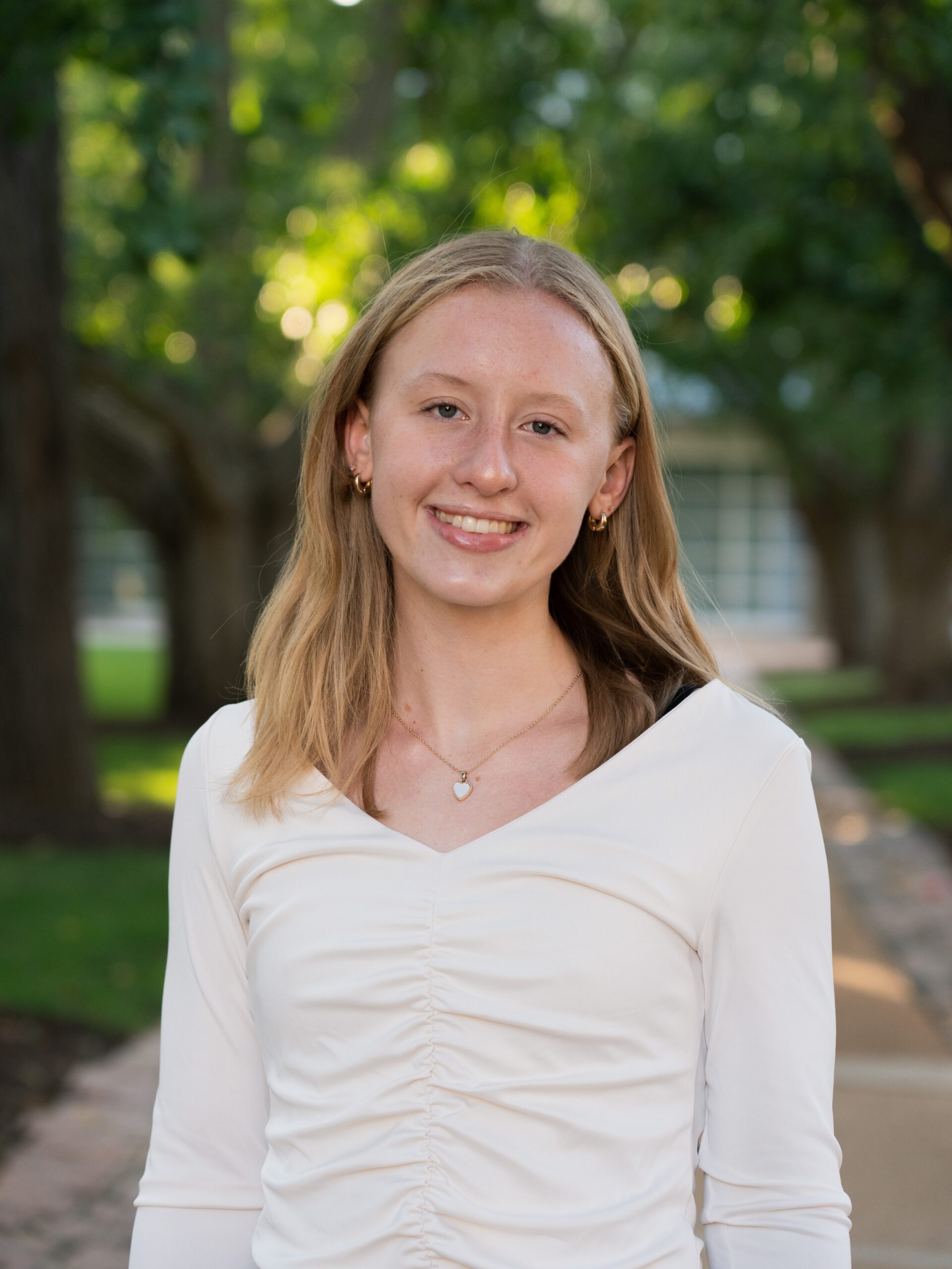 Meghan Jachna, student at WashU, in a white top in front of trees