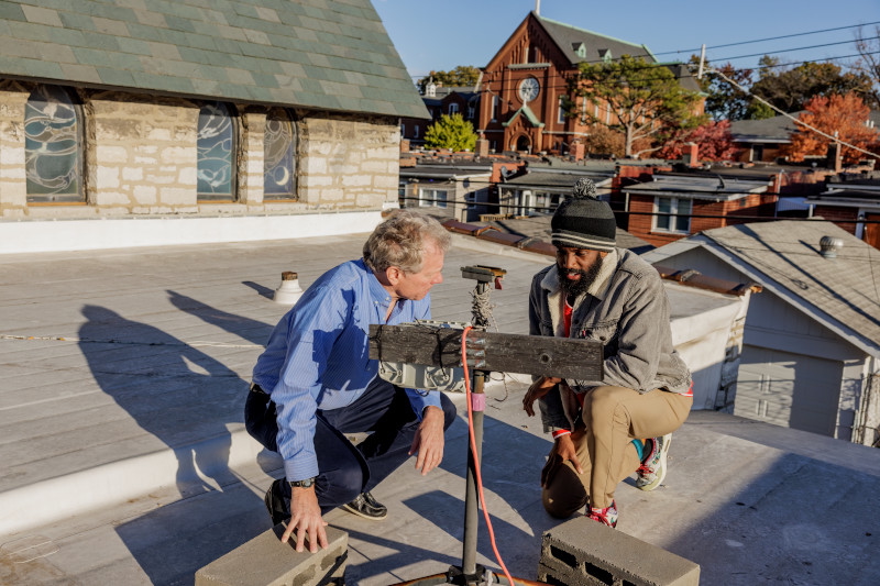 Tyler Cargill (right), a recent PhD graduate of WashU McKelvey Engineering, looks over air monitoring equipment on a roof in south St. Louis with his adviser, Jay Turner, the James McKelvey Professor of Engineering Education